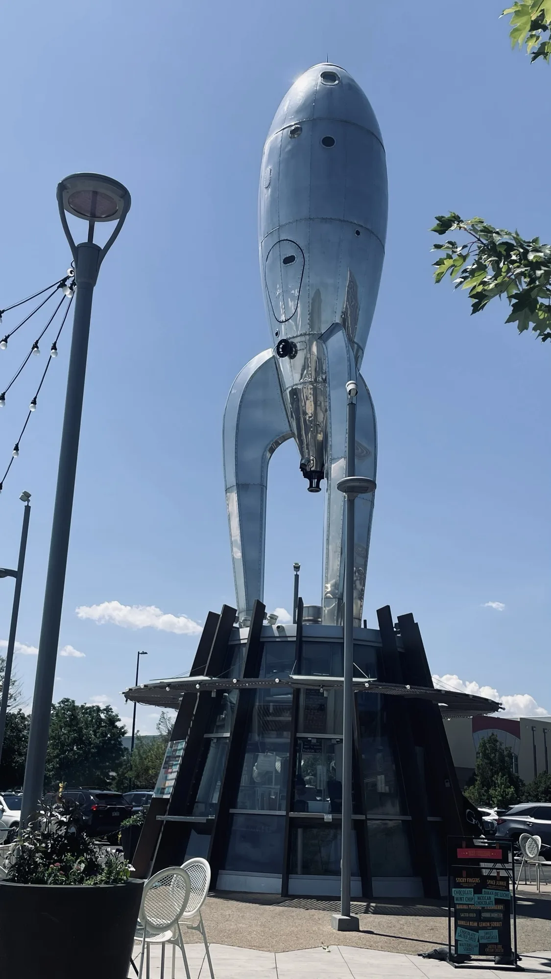 Coffee kiosk with a large silver metal rocket, which is styled like a jet-age 1950’s rocket, all rounded and streamlined